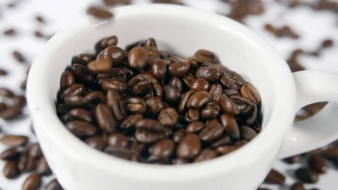 Coffee beans poured into a white ceramic cup with individual arabica beans Stock Footage 88514358