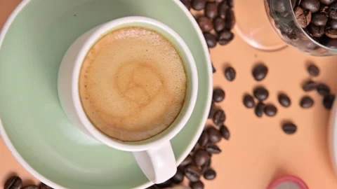 Coffee beans pouring onto the table. Cup of espresso coffee. Vertical video for Video stock 156495174