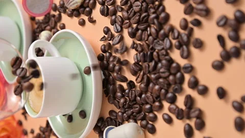 Coffee beans pouring onto the table. Cup of espresso coffee. Vertical video for Video stock 156495226