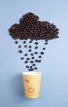 Coffee Beans Rain Cloud Pouring into Paper Cup on Blue Background Stock Photos