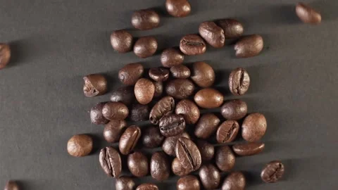 Coffee beans rotating in magic movement into center in slow motion on dark gray Stock Footage 150060208