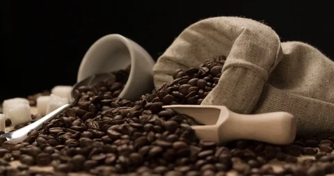 Coffee beans scattered from bag with cup rotating Medium shot Stock Footage 98244281