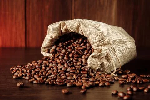 Coffee beans scattered of the bag on table Stock Photos