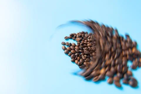 Coffee beans scattered on a blue background with a blurred motion effect, s.. Stock Photos