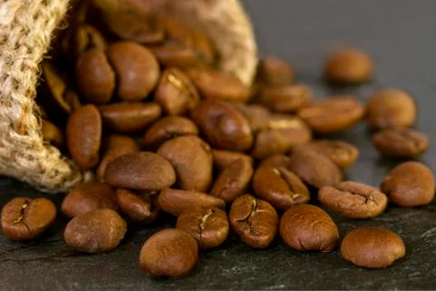 Coffee beans spilling from textile with on the table. Close. Stock Photos