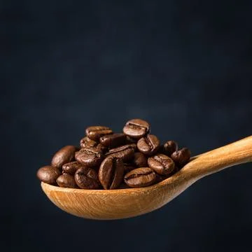 Coffee beans in a spoon on gray background Stock Photos