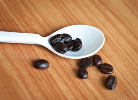 Coffee beans in a spoon . Stock Photos