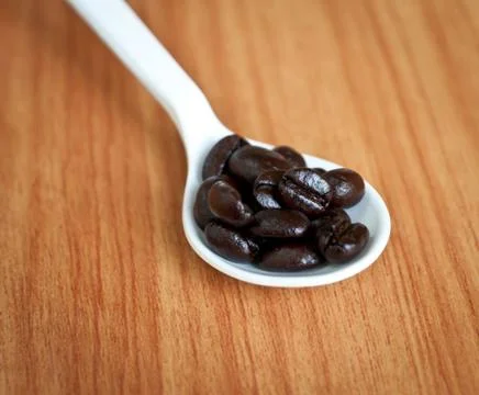 Coffee beans in a spoon . Stock Photos