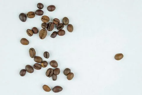 Coffee beans spread on a plain white surface Stock Photos