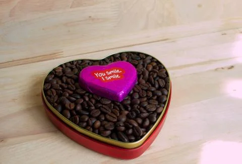 Coffee beans surrounded Chocolate wrapper on Valentine's Day, Wood background Foto stock