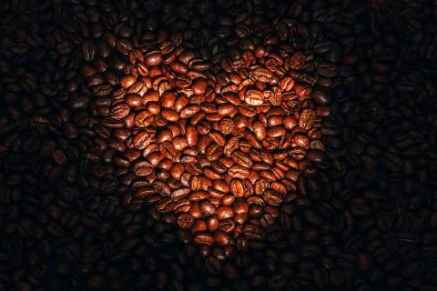 Coffee beans with targeted heart shape lighting. Stock Photos