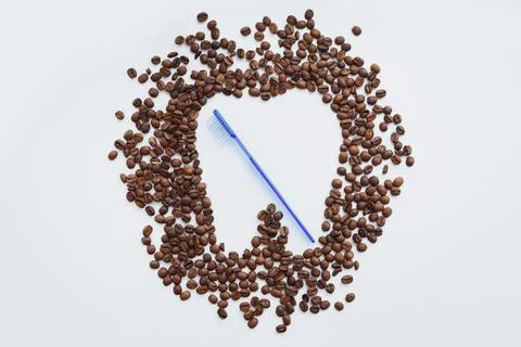Coffee beans in tooth shape and blue toothbrush Stock Photos
