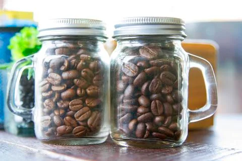 Coffee beans in two bottles placed on the table. Stock Photos