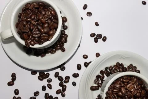 Coffee beans in two coffee cups , on white isolated background.Top view.Creat Stock Photos