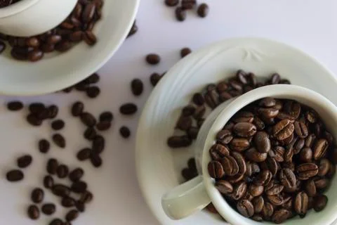 Coffee beans in two coffee cups , on white isolated background.Top view.Creat Stock Photos