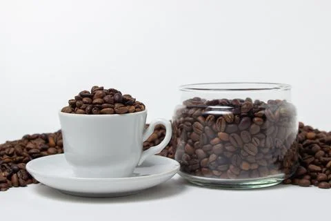 Coffee beans on a white background. A coffee cup full of coffee beans.  Stock Photos