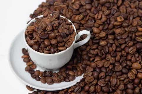 Coffee beans on a white background. A coffee cup full of coffee beans.  Stock Photos