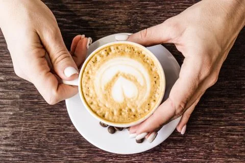 Coffee beans in a white Cup. Hands with a Cup of coffee on the background of  Stock Photos