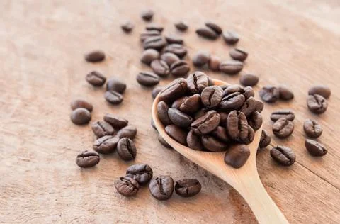 Coffee beans in wooden spoon on wooden background Stock Photos