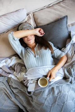 Coffee in bed. Close up top view of young woman having morning coffee while Stock Photos