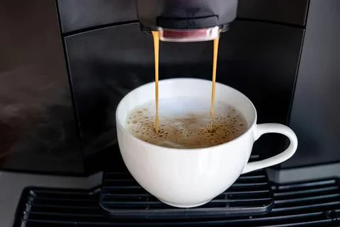 Coffee being brewed in a white cup from a coffee machine Stock Photos