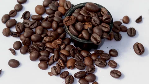 Coffee black roasted beans in capsule falling on table 4k real time Stock Footage 221772167