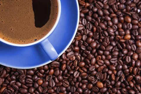 Coffee in blue cup on a table surrounded by coffee beans. Coffee in the shape Stock Photos