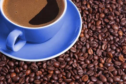 Coffee in blue cup on a table surrounded by coffee beans. Coffee in the shape Stock Photos