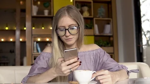 Coffee break. Female using smartphone while drinking coffee Stock Footage 83942887