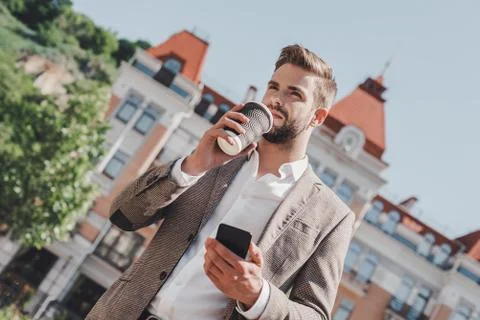 Coffee break on a go. Low angle view of confident brown-haired man holding Stock Photos