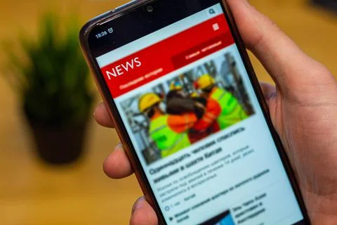 Coffee break in the office while reading news on the cellphone. 写真素材