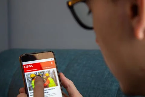 Coffee break in the office while reading news on the cellphone. Stock Photos