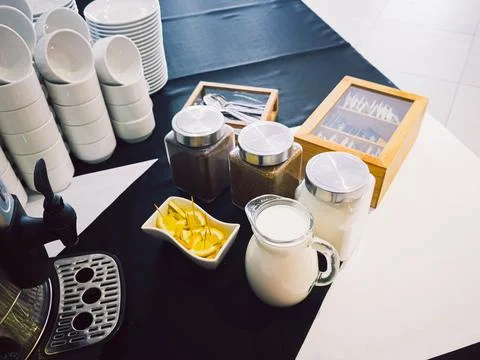 Coffee break setup with cups, milk, lemon and tea jars on tablecloth Stock Photos