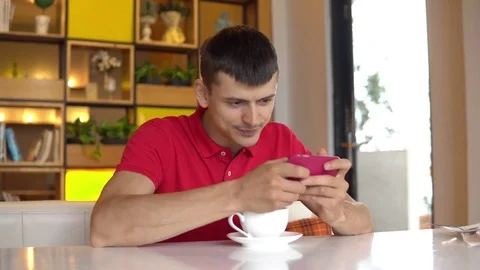 Coffee break. Young man play game on cell phone Stock Footage 83966770