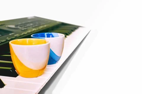 Coffee break,relax.Two yellow blue cups on synth piano keys Stock Photos