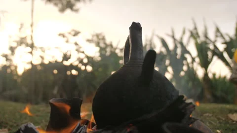 The coffee is brewing and heating in a coffee pot over an outdoor fire Stock Footage 336367889