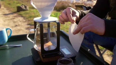 Coffee brewing outdoors - inserting paper filter into brewer Stock-Footage 165110342