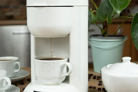 Coffee brewing process in a coffee machine, hot coffee is poured into a cup. Stock Photos