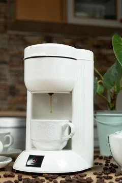 Coffee brewing process in a coffee machine, hot coffee is poured into a cup. Stock Photos
