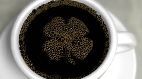 Coffee bubbles in a white porcelain cup pop to reveal four leaf clover animation Stock Footage 61490229