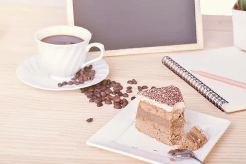 Coffee cake and cup with notepad ,blackboard on office table. copy space Foto stock