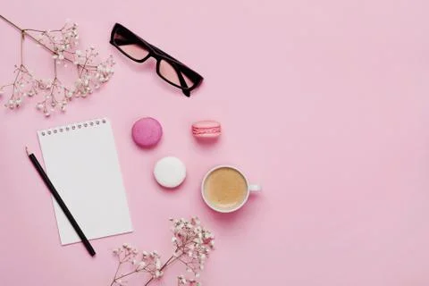 Coffee, cake macaron, clean notebook, eyeglasses and flower on p Stock Photos