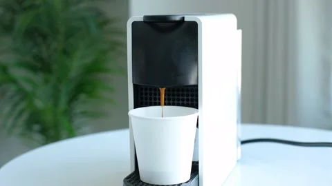 Coffee from a capsule coffee machine is poured into white paper cup close-up. Stock Footage 234863787