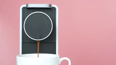 Coffee from capsule coffee machine is poured into white cup close-up on pink Stock Footage 270279765