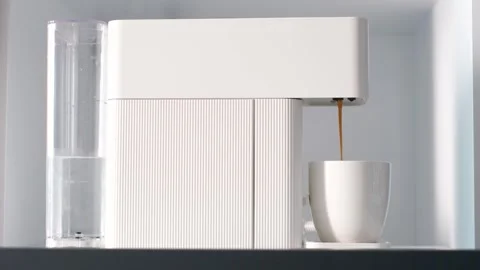 Coffee from capsule coffee machine is poured into white cup close-up, side view. Stock Footage 290298817