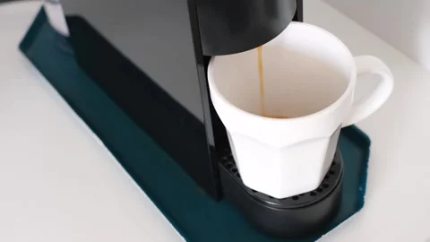 Coffee from capsule coffee machine is poured into white cup. Stock Footage 323260320