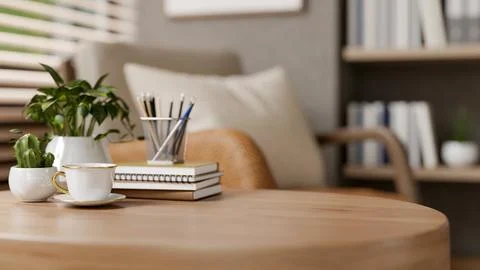 Coffee in ceramic cup and books on round wooden table with armchair aside b.. Stock Illustration