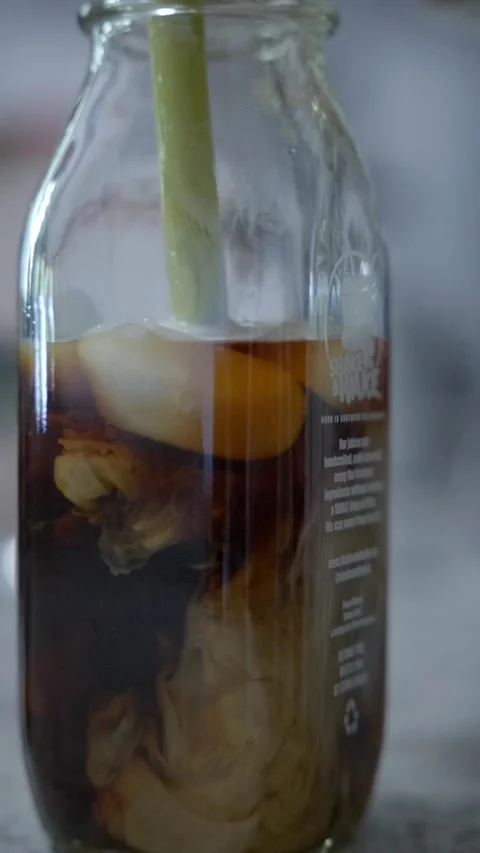 Coffee creamer diffusing into a cold brew glass bottle Video stock 232845821