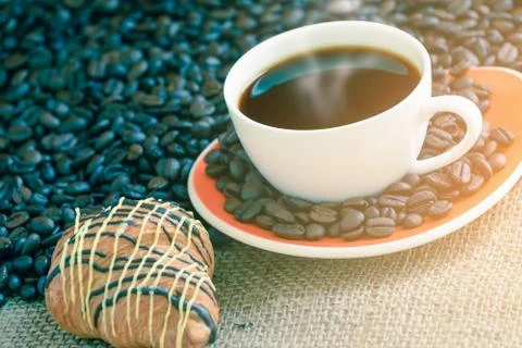 Coffee cup and bread on sack with coffee bean, focused on a cup. Stock Photos