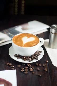 Coffee cup and coffee beans on wooden table. Stock Photos